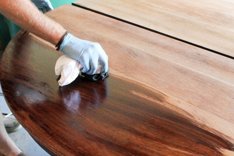 close shot of a hand applying paste wax on a wood table.