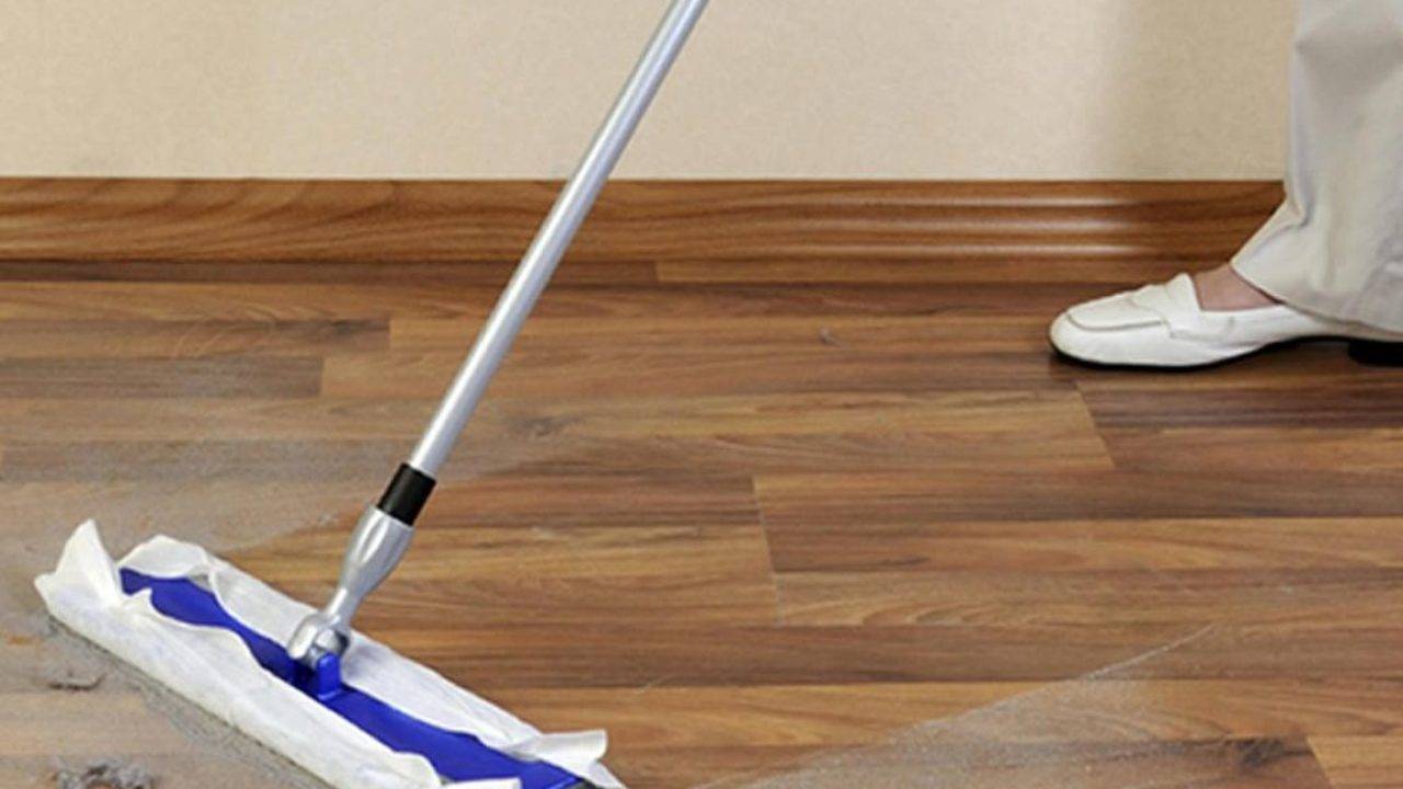 applying slip resistant coating on the hardwood floor with mop.